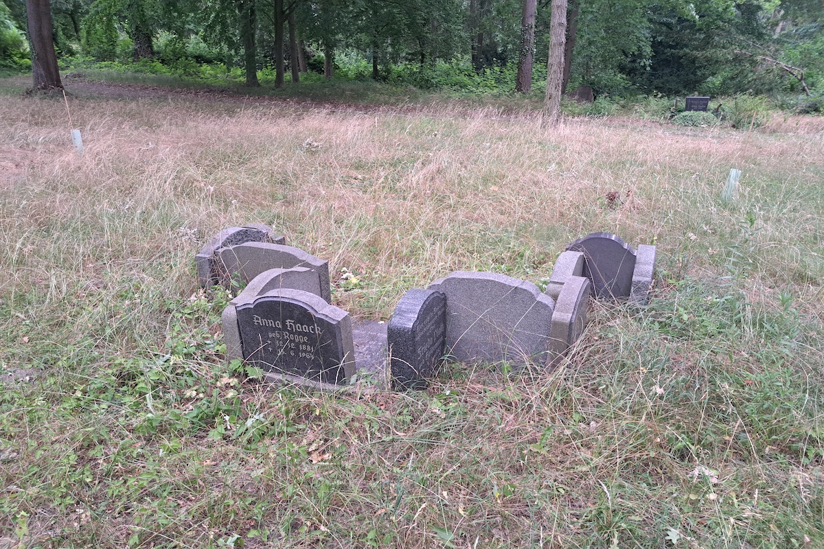 Eine Gruppe Grabsteine auf einer Wiese.
